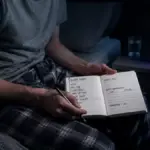 A survivor sitting in a dark bedroom struggling with chronic insomnia after chemotherapy