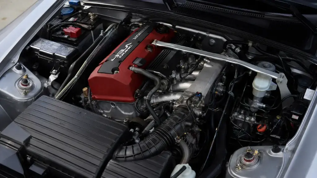 Clean engine bay of a Honda S2000 highlighting the red valve cover next to a Porsche Boxster comparison.