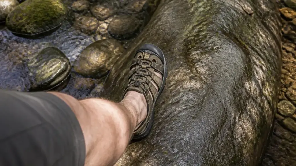 senior hiker feet in supportive sandals crossing stream following physical activity recommendations.

