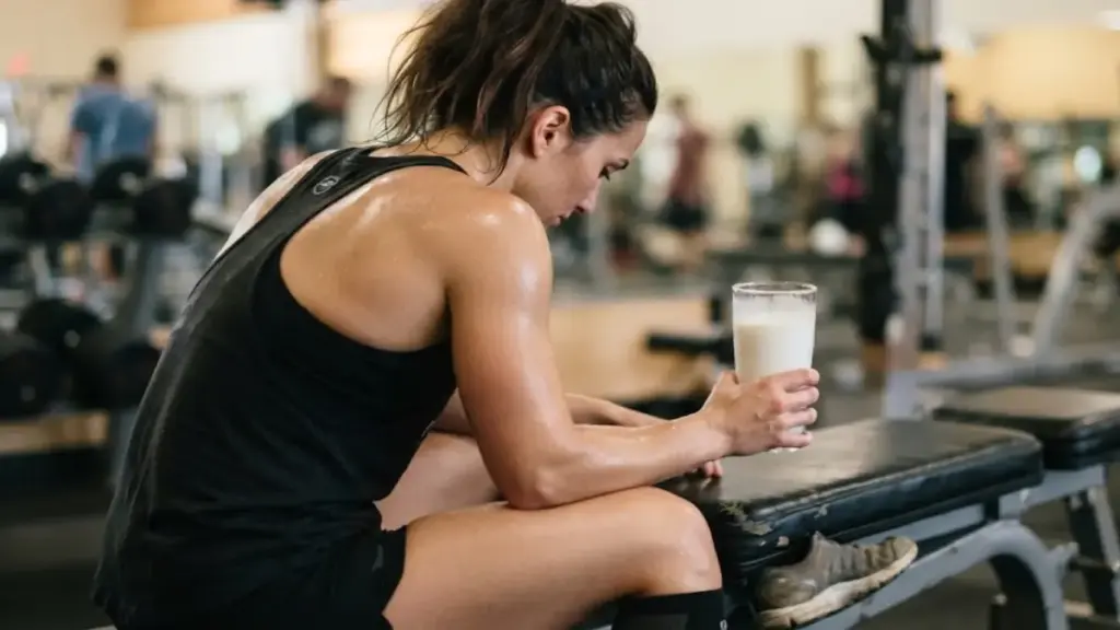 athlete-sitting-on-a-bench-holding-a-glass-of-cold-milk-after-exercise

