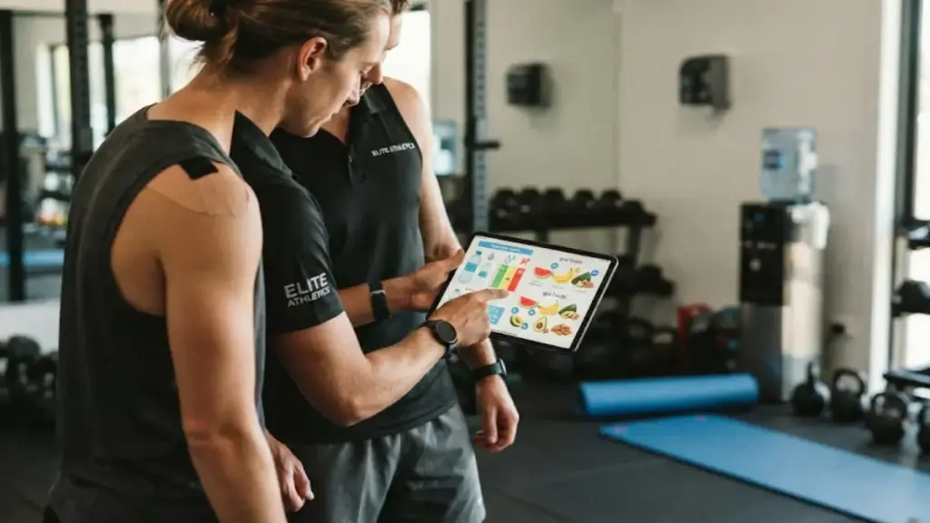 fitness-trainer-explaining-hydration-charts-on-a-tablet-to-an-athlete