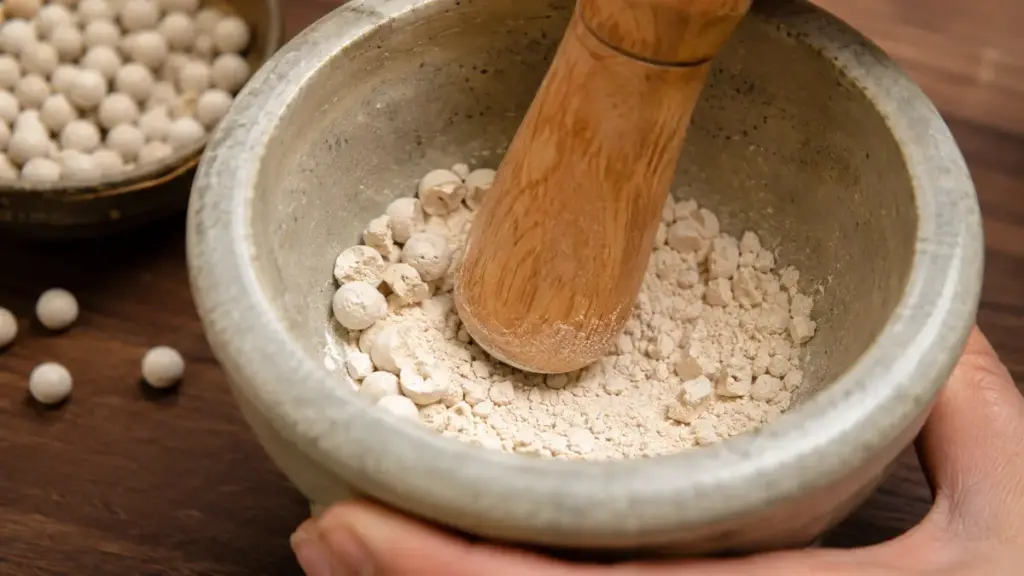 grinding-white-rice-yeast-balls-into-fine-powder-using-a-wooden-pestle
