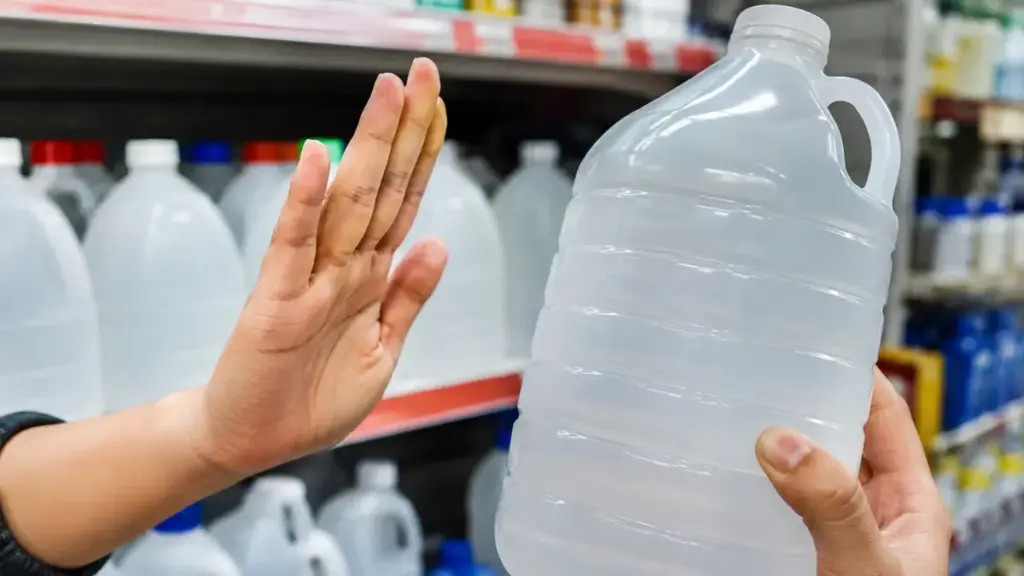 hand-passing-by-large-industrial-plastic-jugs-of-cheap-bulk-rubbing-alcohol