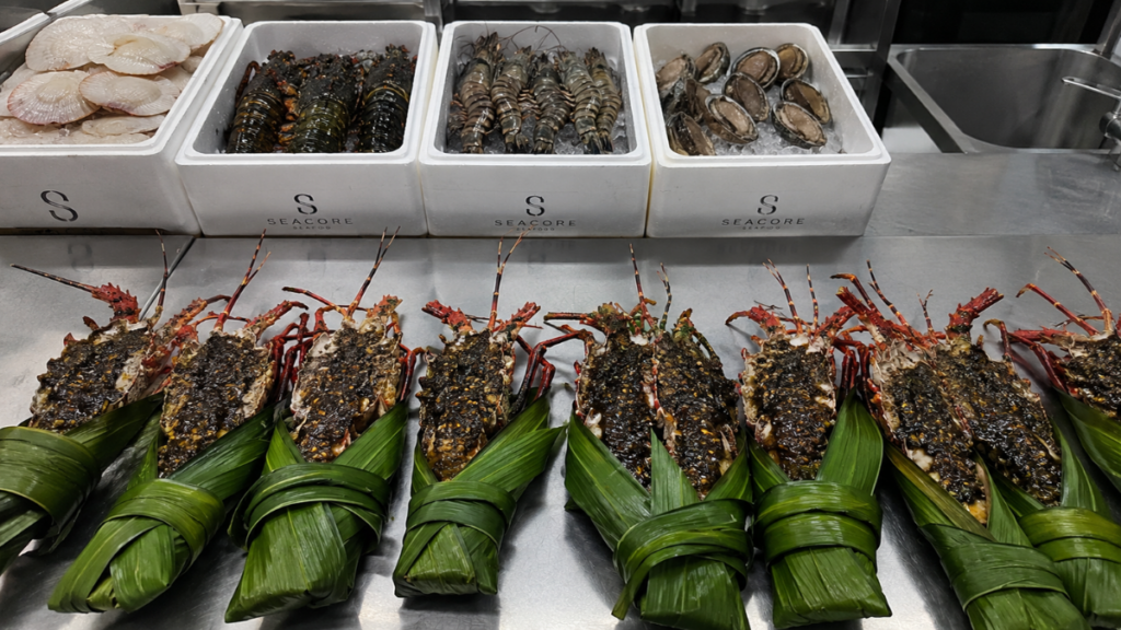 Split fresh lobsters with black garlic butter sauce representing the 4 must-have foods for an outdoor cookout list
