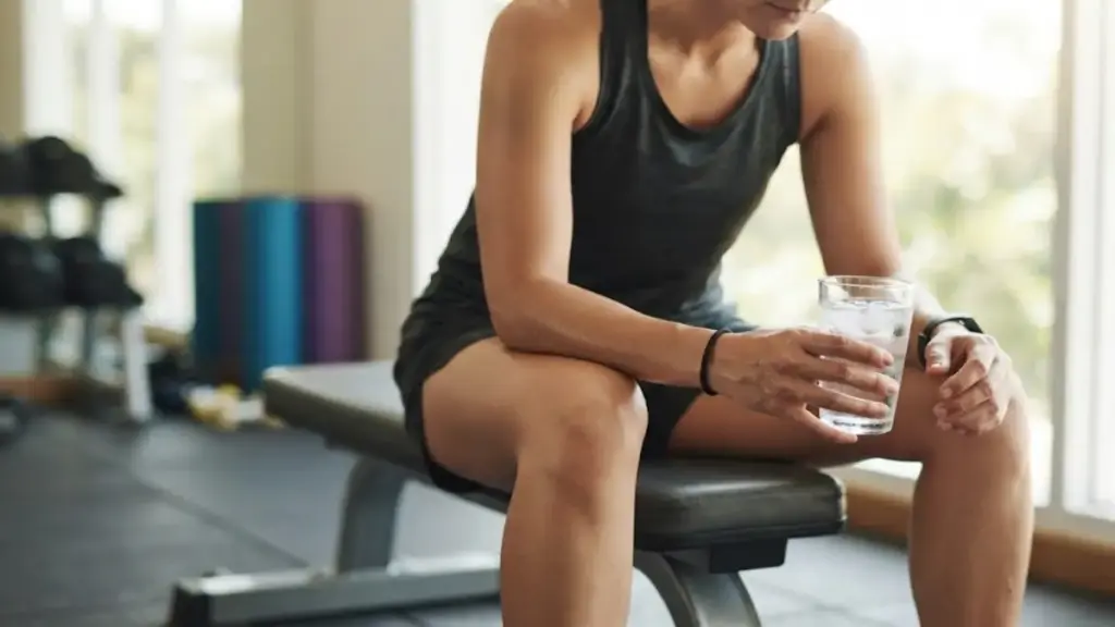 person-sitting-on-a-bench-holding-a-glass-of-fresh-water
