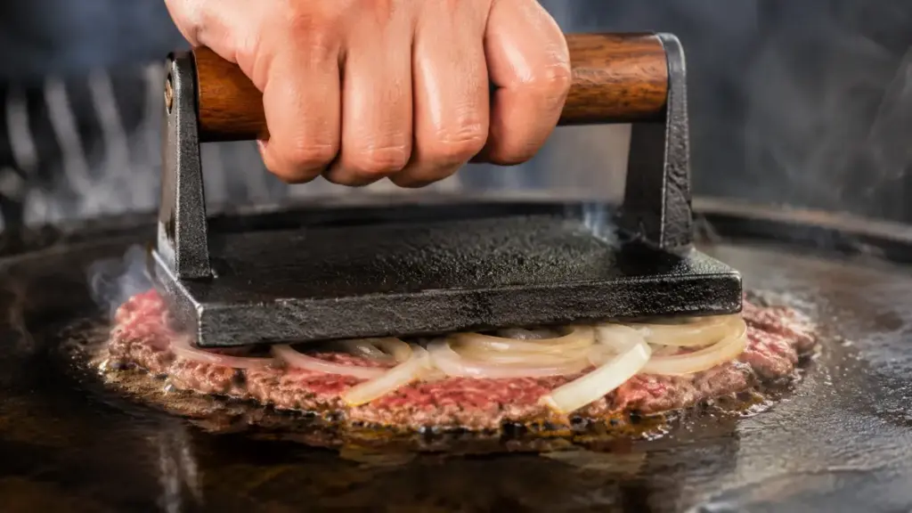 pressing-thin-onion-slices-into-searing-beef-on-a-skillet