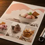 printed dessert menu placed next to a metal scoop on a table