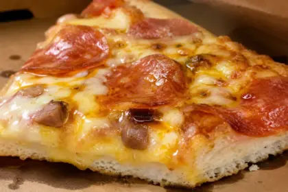 processed fast food pizza slice showing heavy grease buildup and thick industrial crust textures