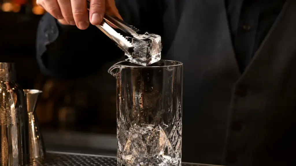 professional-bartender-chilling-spirits-with-dense-clear-ice-in-a-crystal-glass-ukl