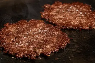 sizzling hot thin smash burger patties with crisp caramelized edges on a cast iron griddle