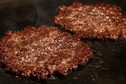 sizzling hot thin smash burger patties with crisp caramelized edges on a cast iron griddle
