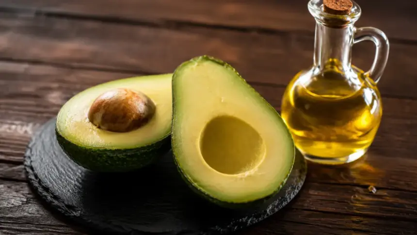 sliced fresh green avocado and olive oil on a slate plate aft
