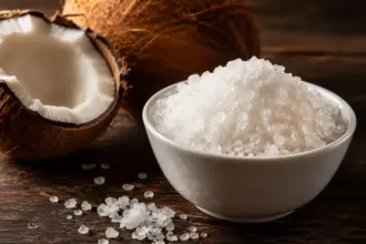 white bowl of celtic sea salt crystals and a cracked coconut