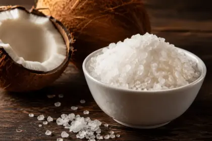 white bowl of celtic sea salt crystals and a cracked coconut