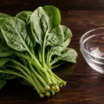 fresh green leafy vegetable placed next to a glass bowl on a table