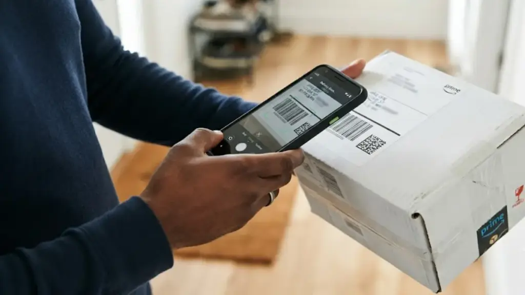 A person using a smartphone to scan an Amazon Prime package for secure online shopping
